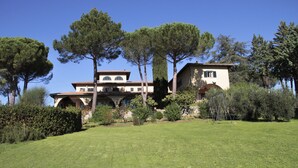 Une maison à deux étages avec un jardin, entourée d’arbres.