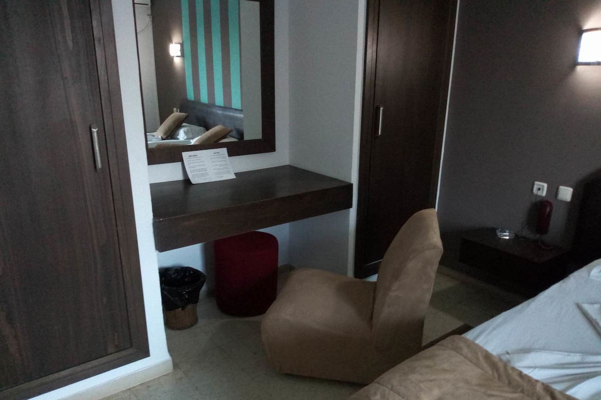 Une chambre à coucher comprenant un lit, une chaise, un bureau, un miroir et une armoire.