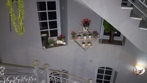 A multi-level interior with a spiral staircase, potted plants on shelves, and a decorative railing. - Diar Mariem Hotel (Port El Kantaoui)