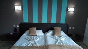 A double bed with two pillows, a bedside table, and a wall-mounted light fixture. - Diar Mariem Hotel (Port El Kantaoui)