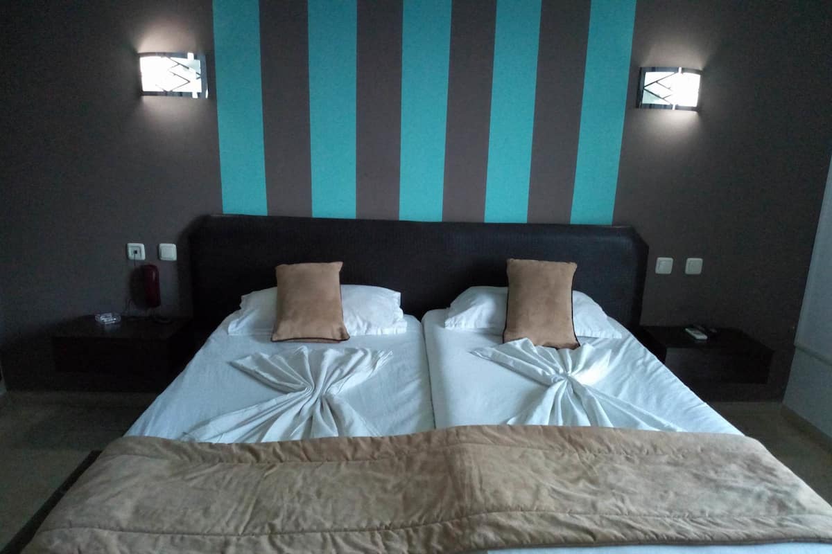 Un lit double avec deux oreillers, une table de chevet et un luminaire fixé au mur.