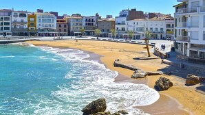 Un pueblo costero con una playa arenosa, un litoral rocoso y edificios coloridos a lo largo del paseo marítimo.