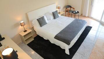 Una camera d'albergo con un letto grande, due comodini con lampade, una poltrona e vista sull'esterno.