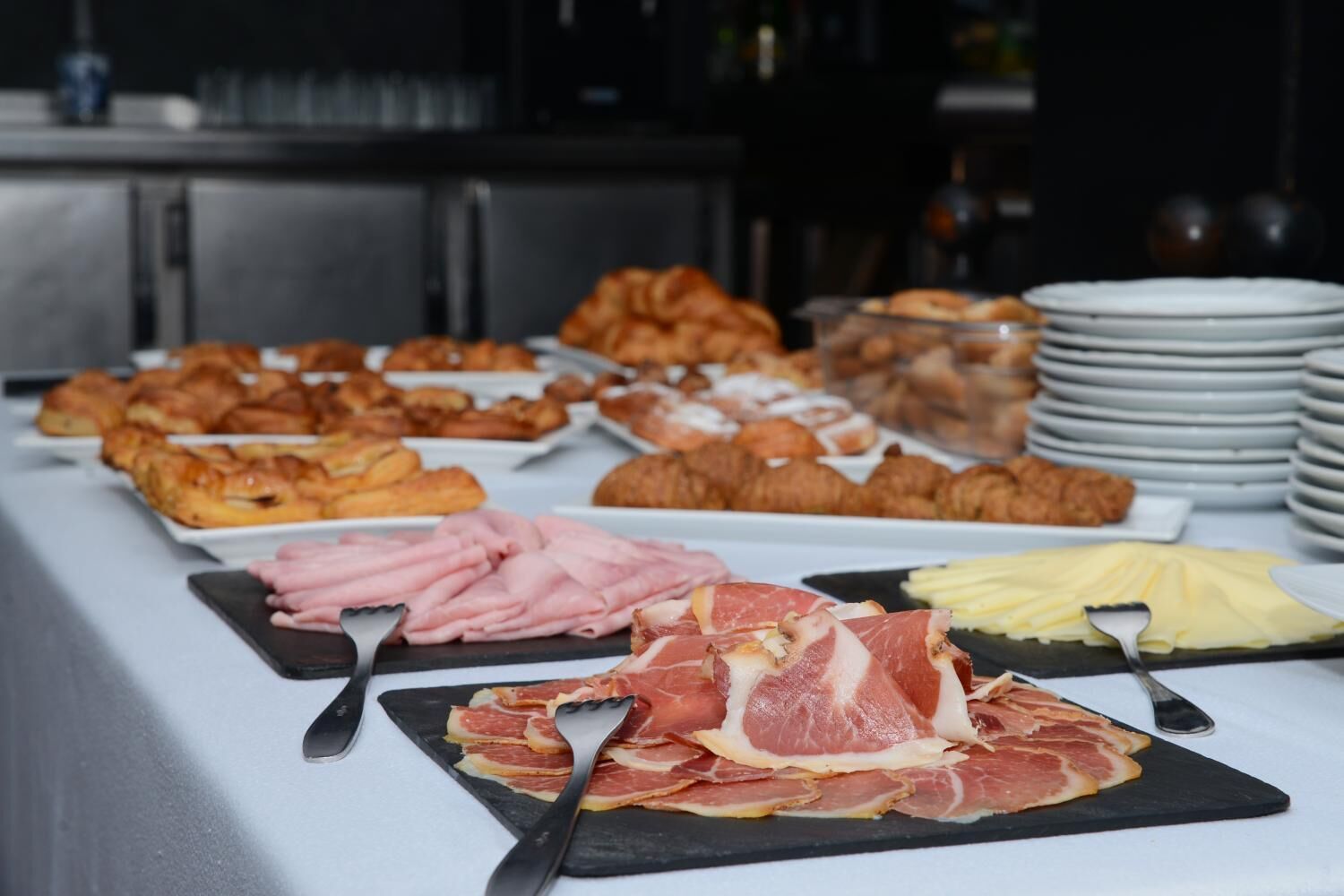 Een buffet met diverse gerechtjes, waaronder gebak, vleeswaren en kaas.