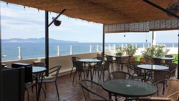 Ulkoterassi, jossa on rottinkihuonekaluja ja -pöytiä, ja josta avautuu näkymä vesistöön ja kaukaisiin vuorille.