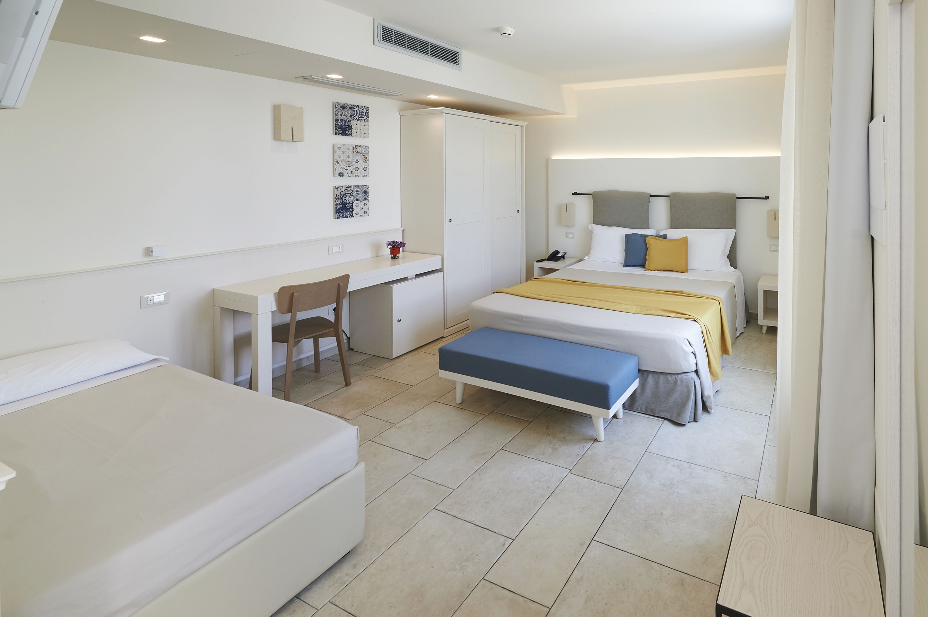 Ein Hotelzimmer mit zwei Betten, einem Schreibtisch, einem Stuhl und einem Kleiderschrank.