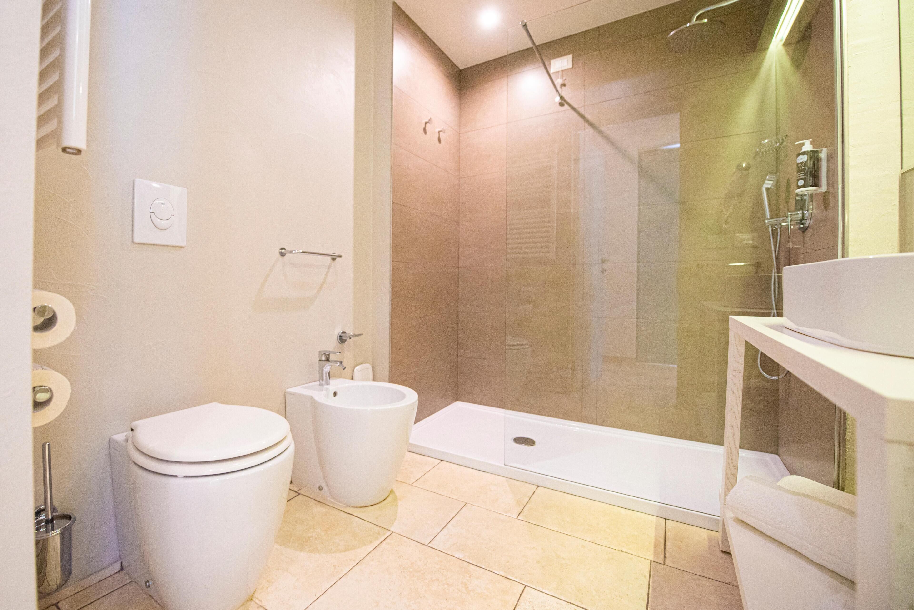 A modern bathroom with a toilet, bidet, and a glass-enclosed shower area.