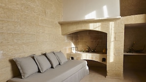 Una habitación con pared de piedra, chimenea, sofá y una pequeña mesa.