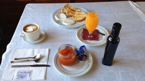Een ontbijttafel met een kop koffie, toast, een glas sinaasappelsap, jam en een thermosfles.