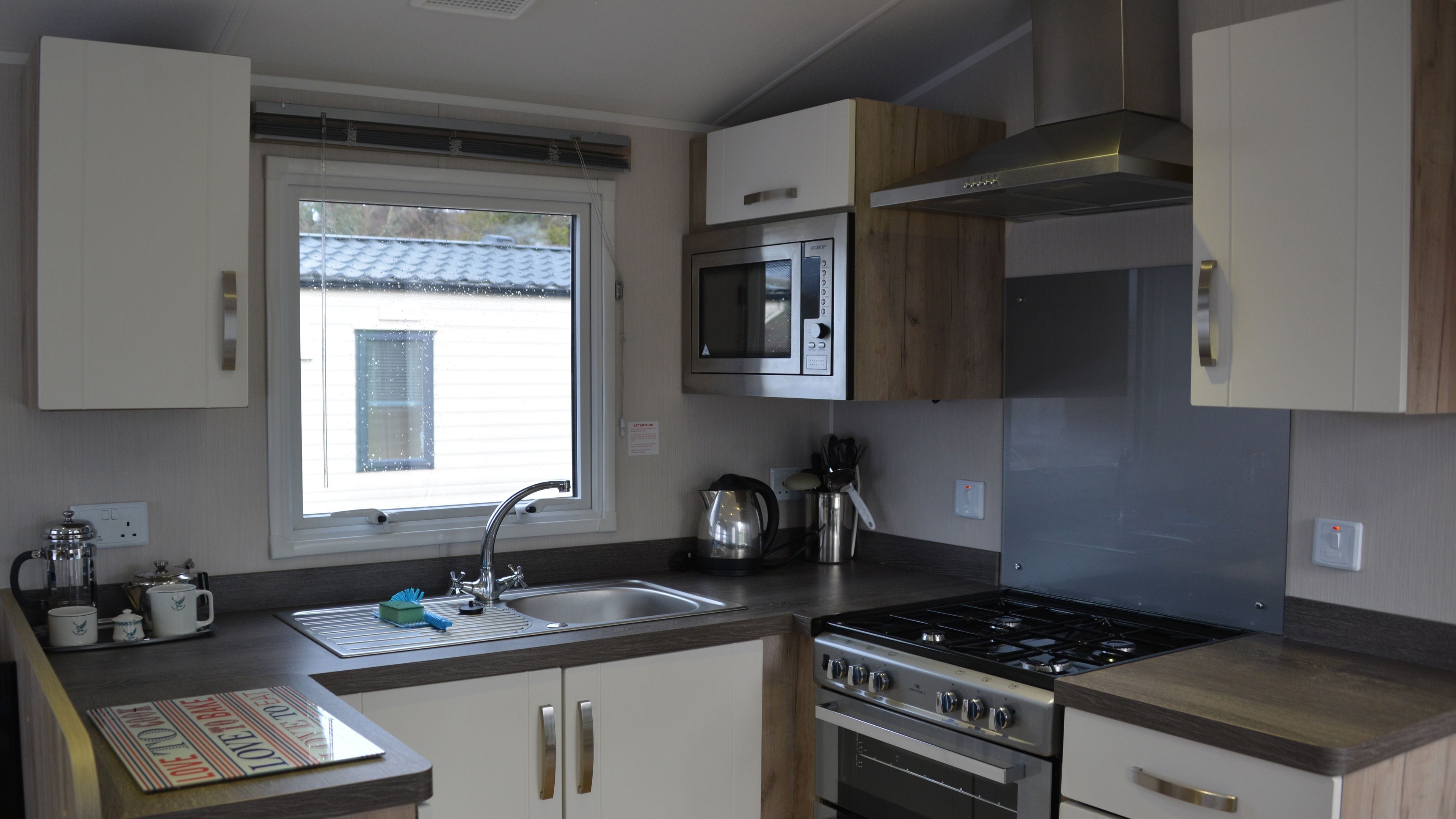 A compact kitchen with a sink, stove, microwave, and cabinets.