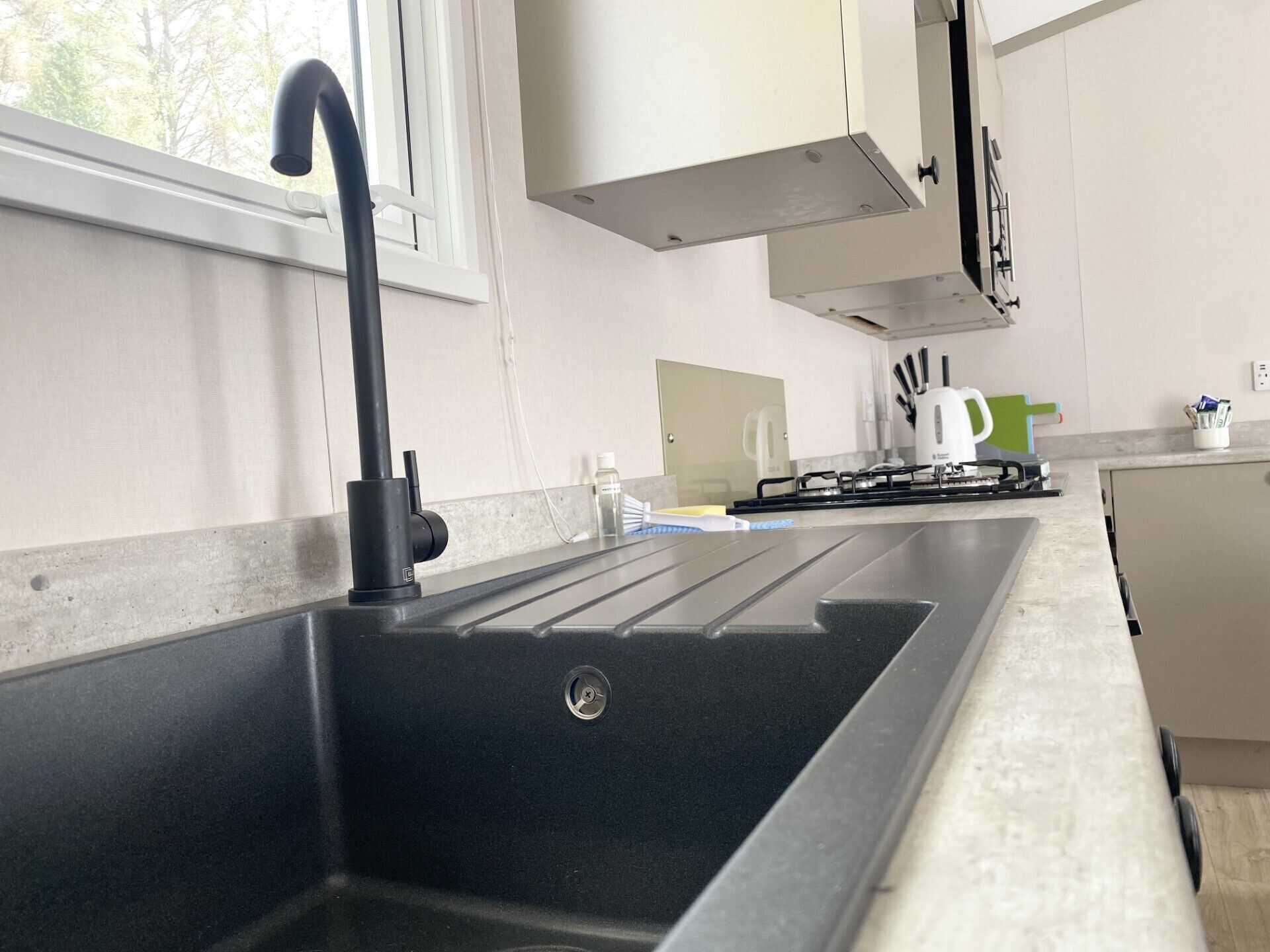 Een moderne keuken met een zwarte spoelbak, roestvrijstalen apparatuur en witte keukenkastjes.