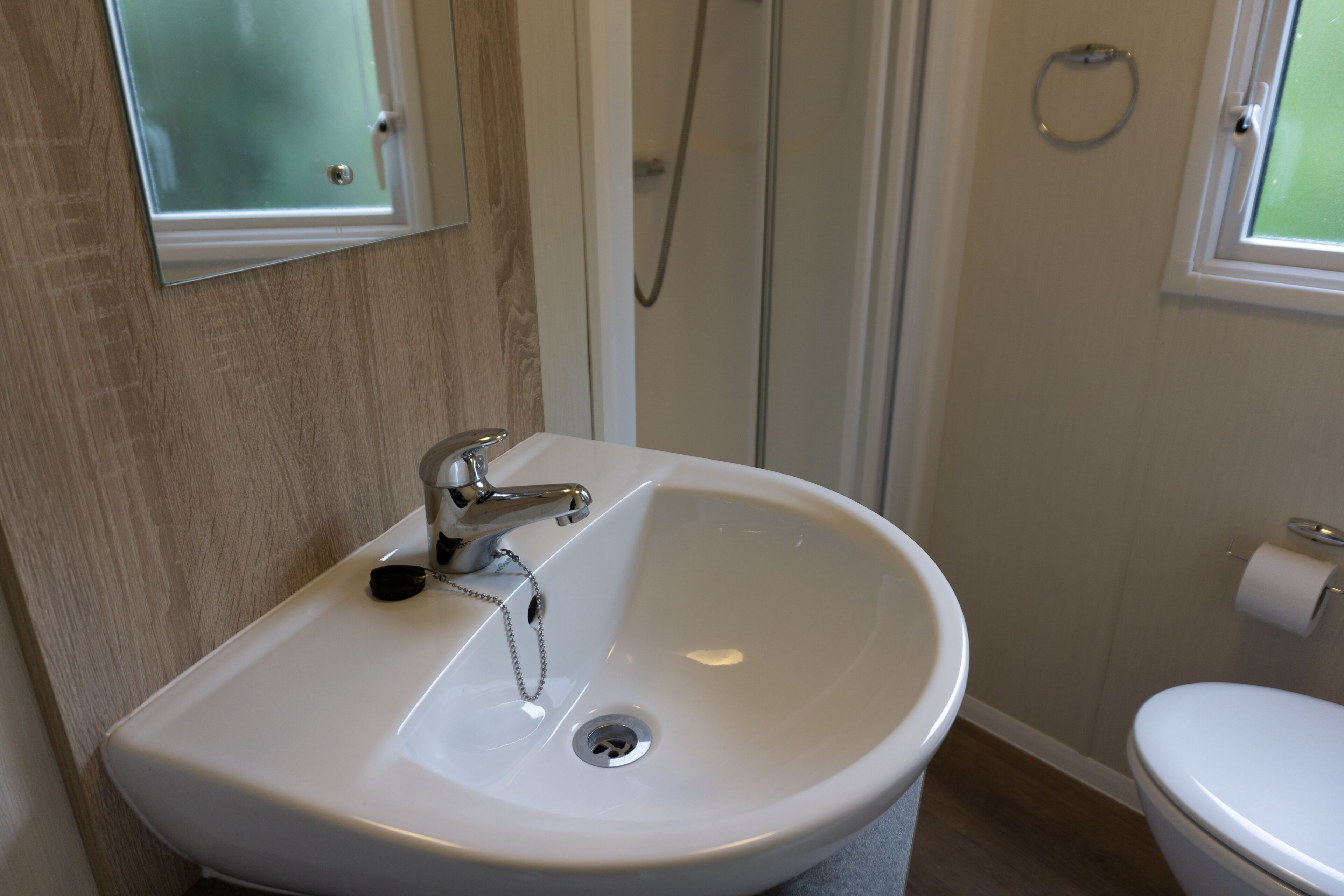 Un baño con lavamanos blanco, un espejo, ducha e inodoro.