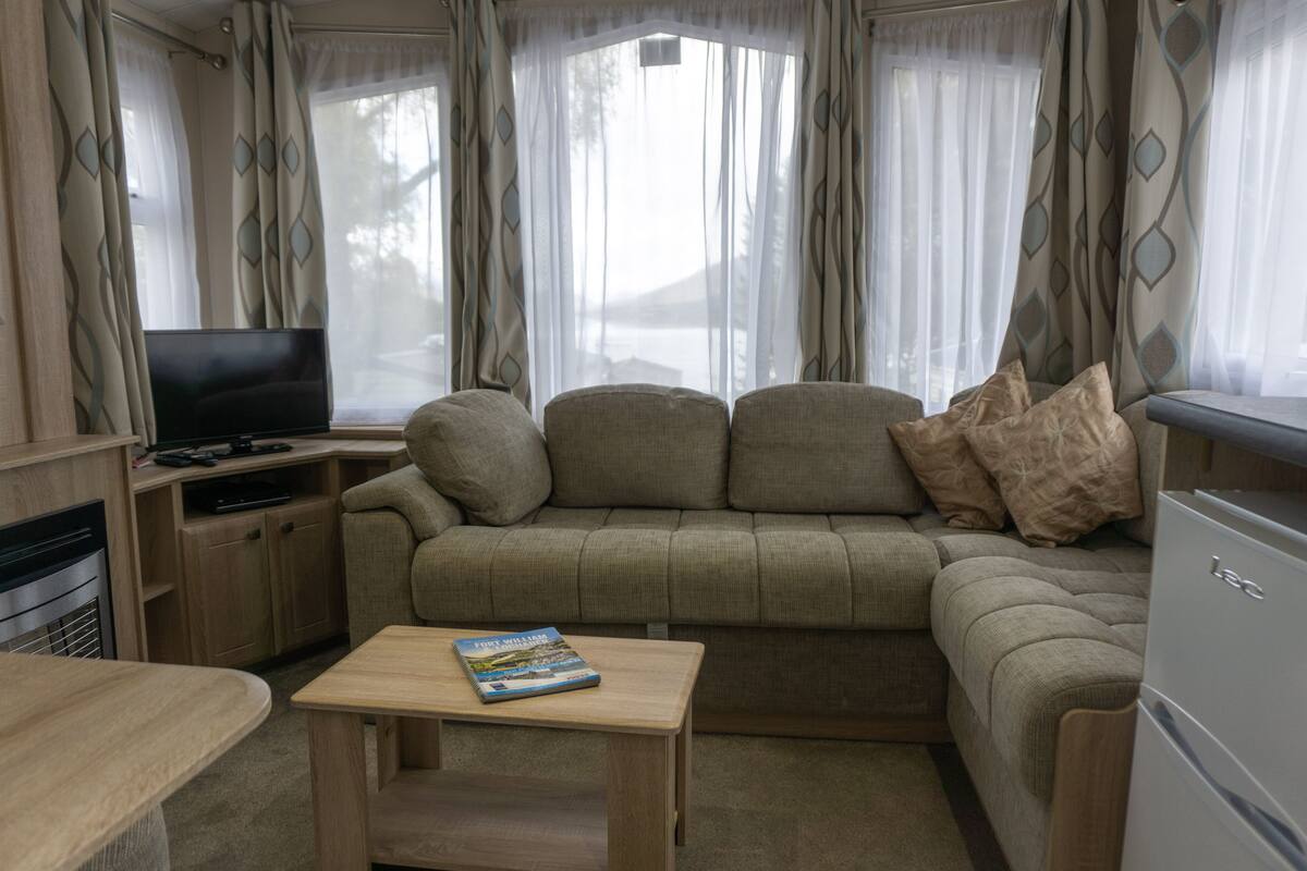 A cozy living area with a sofa, a television, and a small table with a book.