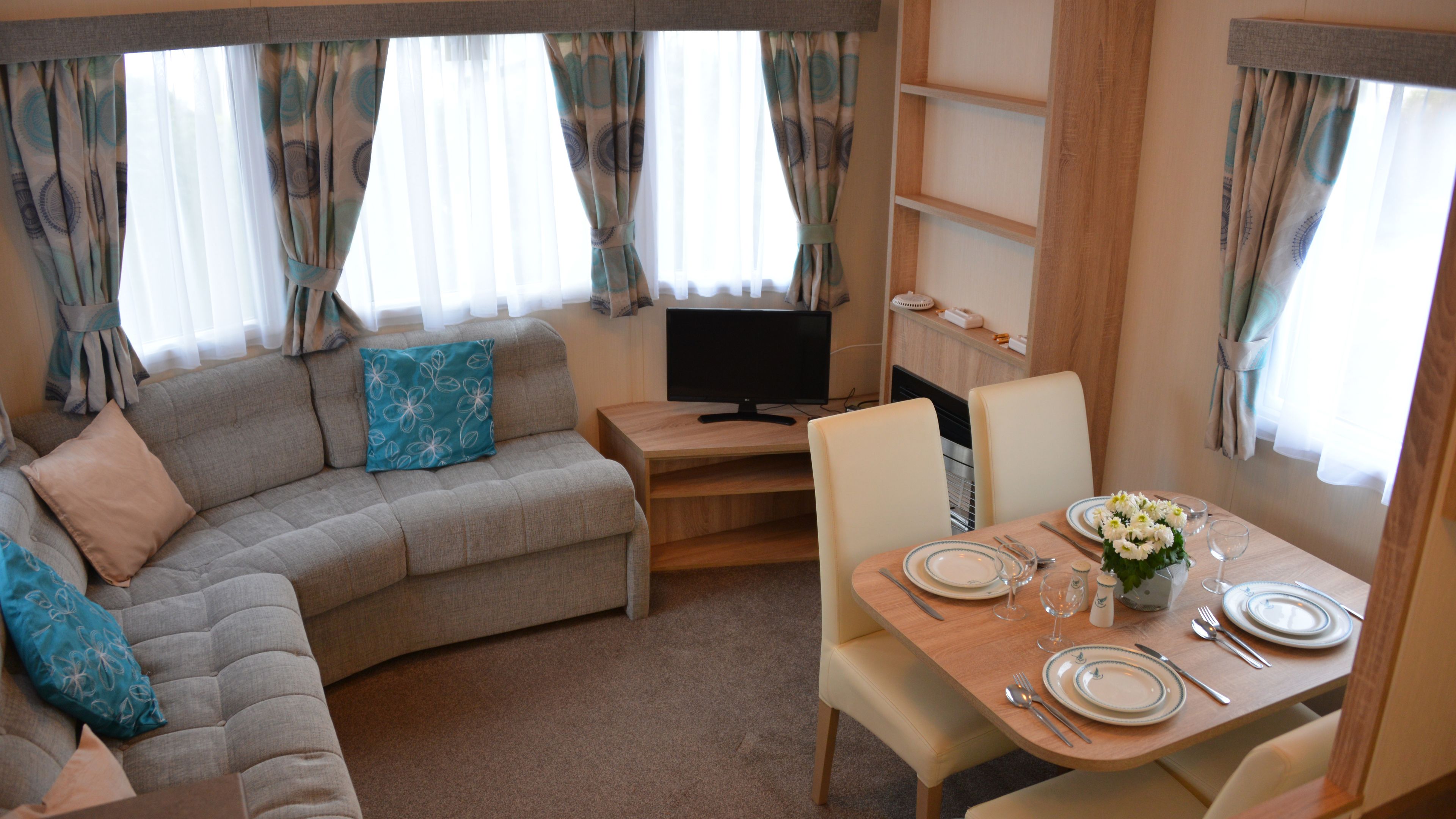 A cozy living area with a sofa, a TV, and a dining table set for two.