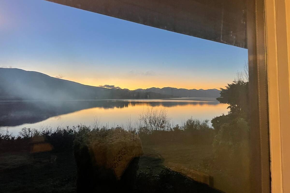 A view of a lake with mountains in the background, viewed through a window.