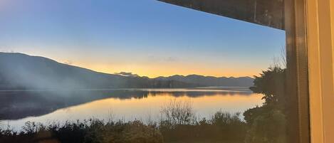 A view of a lake with mountains in the background, viewed through a window.