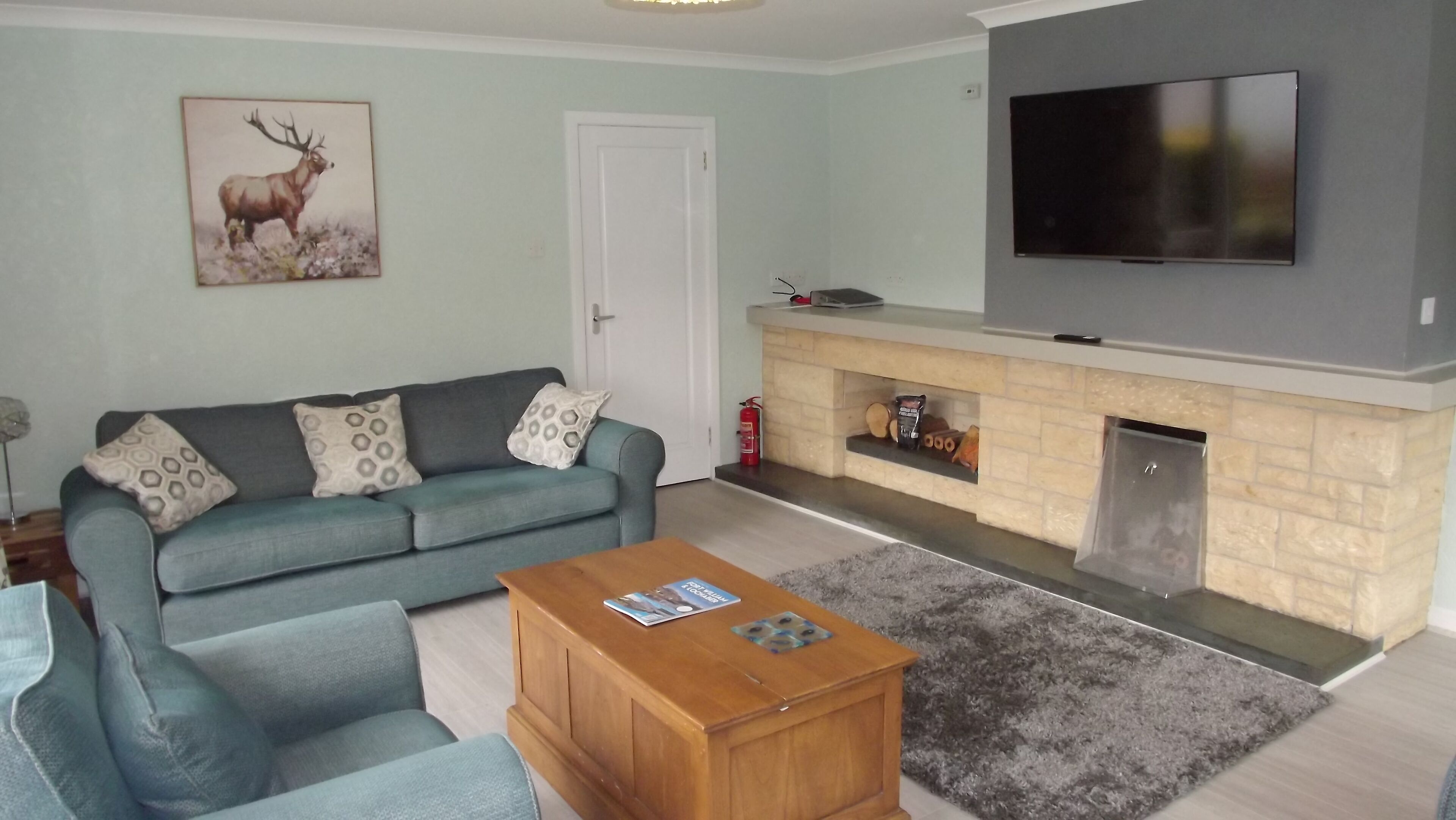 A living room with a sofa, a coffee table, a fireplace, and a television.