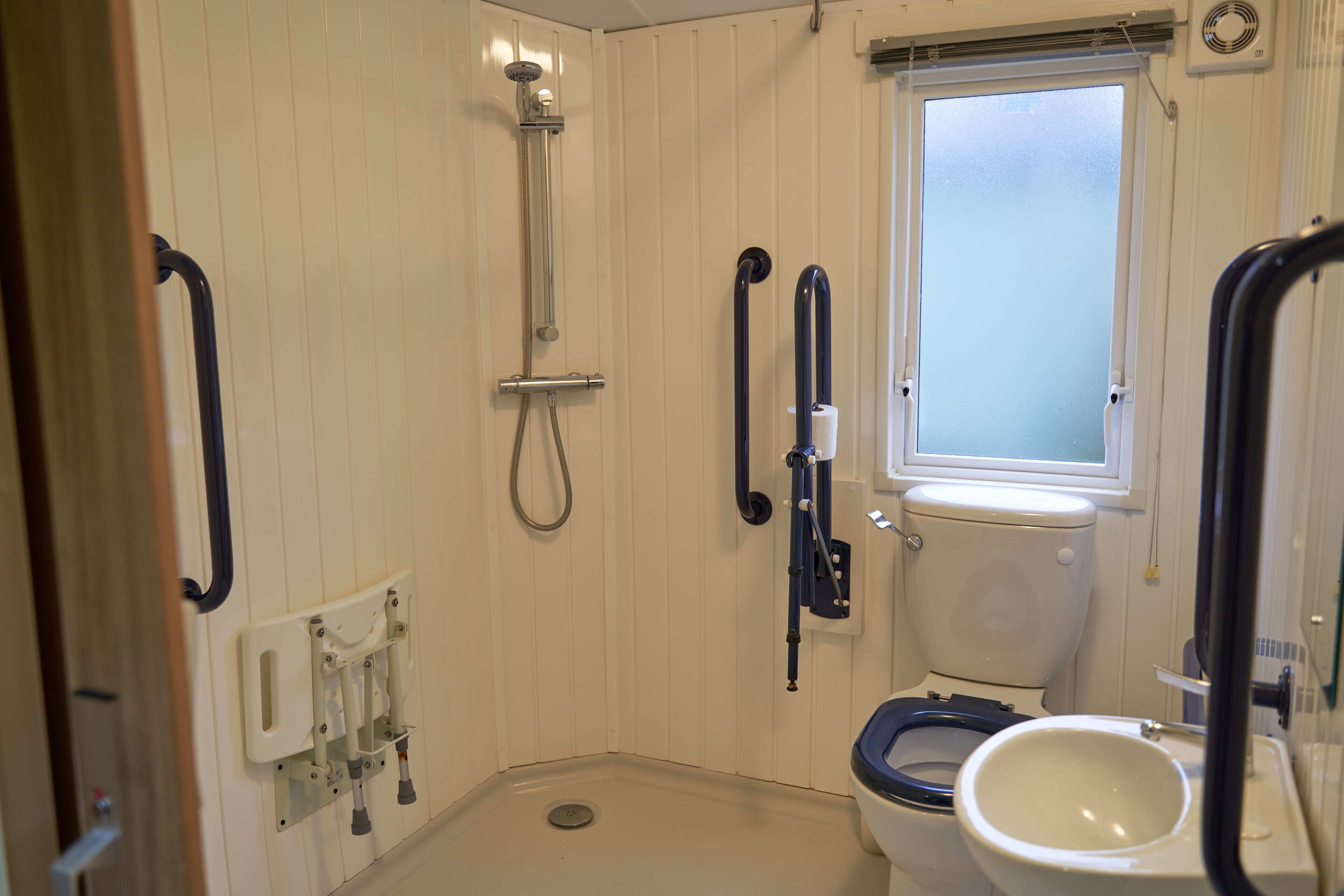 A small, compact bathroom with a shower, toilet, and a window.