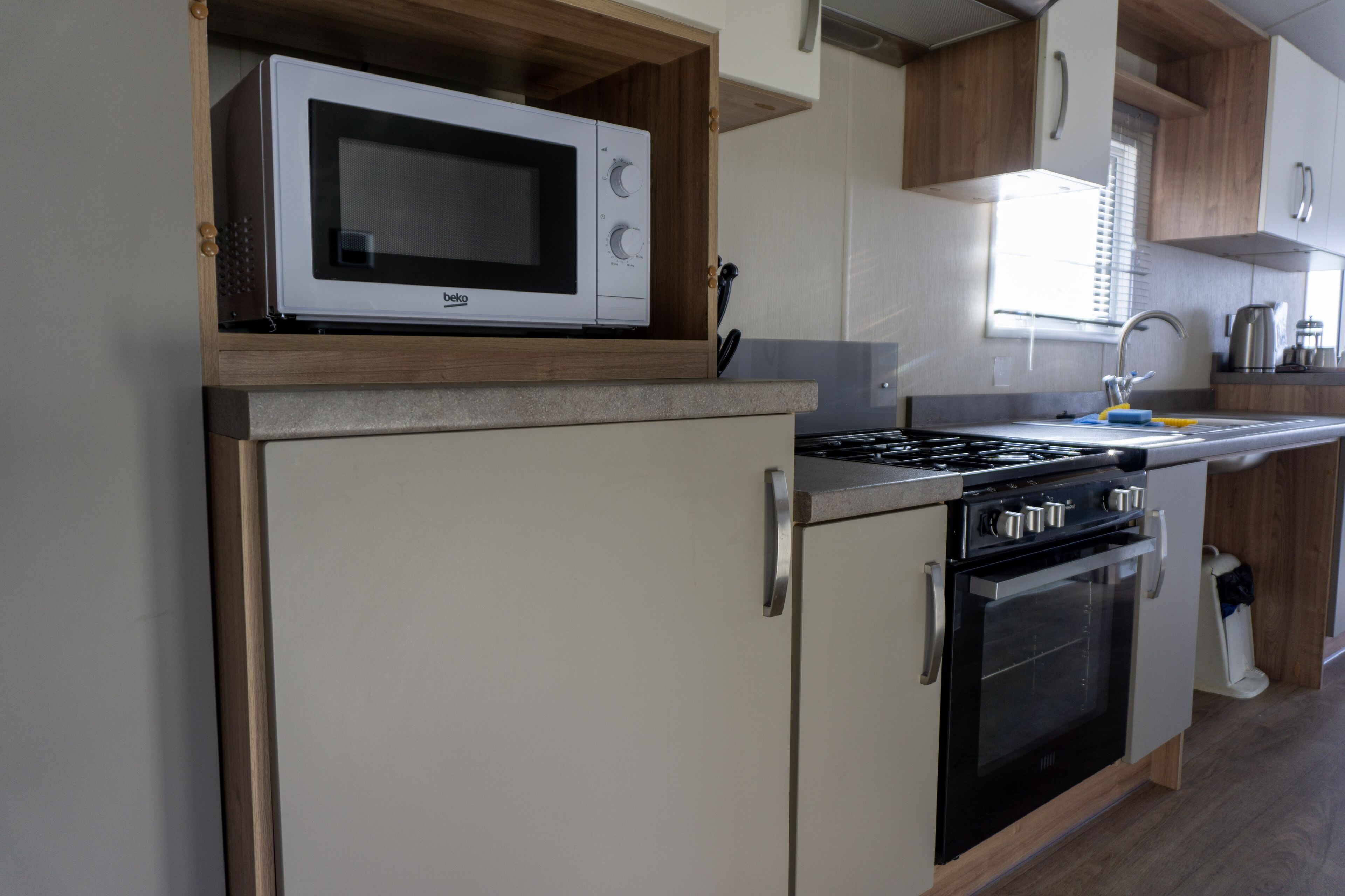A compact kitchenette with a microwave, stove, oven, and sink.