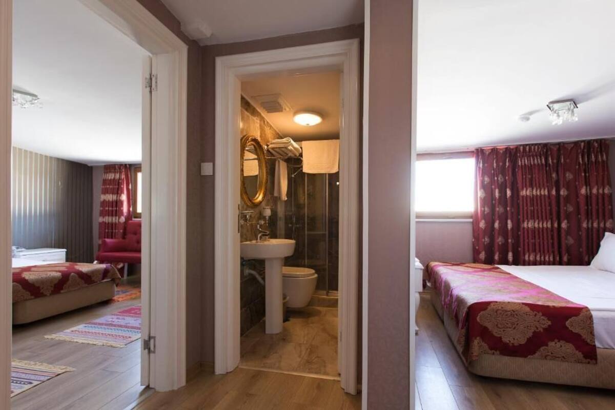 A hotel room with a bed, a bathroom with a sink and toilet, and a red curtain.