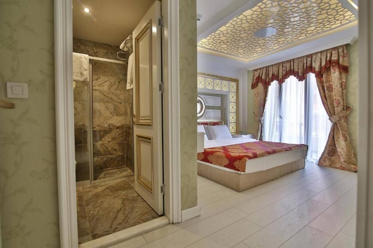 A bedroom with a large bed, a walk-in closet, and a shower area.