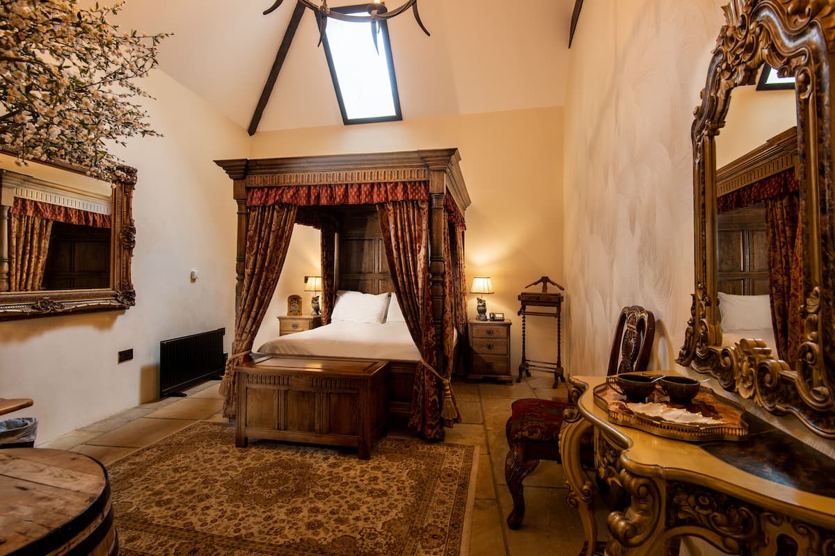 A traditional bedroom with a canopy bed, ornate furniture, and a large mirror.