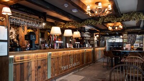 A bar area with wooden counter, multiple lamps, and a sign reading "THE STABLES". - The Stables Whitby (Whitby)