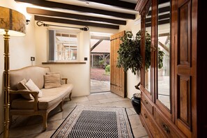 A cozy entryway with a bench, a potted plant, and a wooden cabinet. - The Stables Whitby (Whitby)