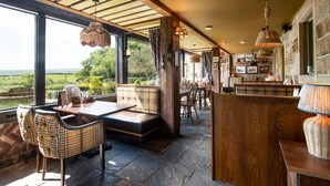 A spacious dining area with a view of the countryside, wooden furniture, and hanging lights. - The Stables Whitby (Whitby)