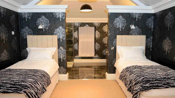 A bedroom with two beds, a large mirror, and a view of a bathroom. - Bishopcleugh Guest House (Lockerbie)