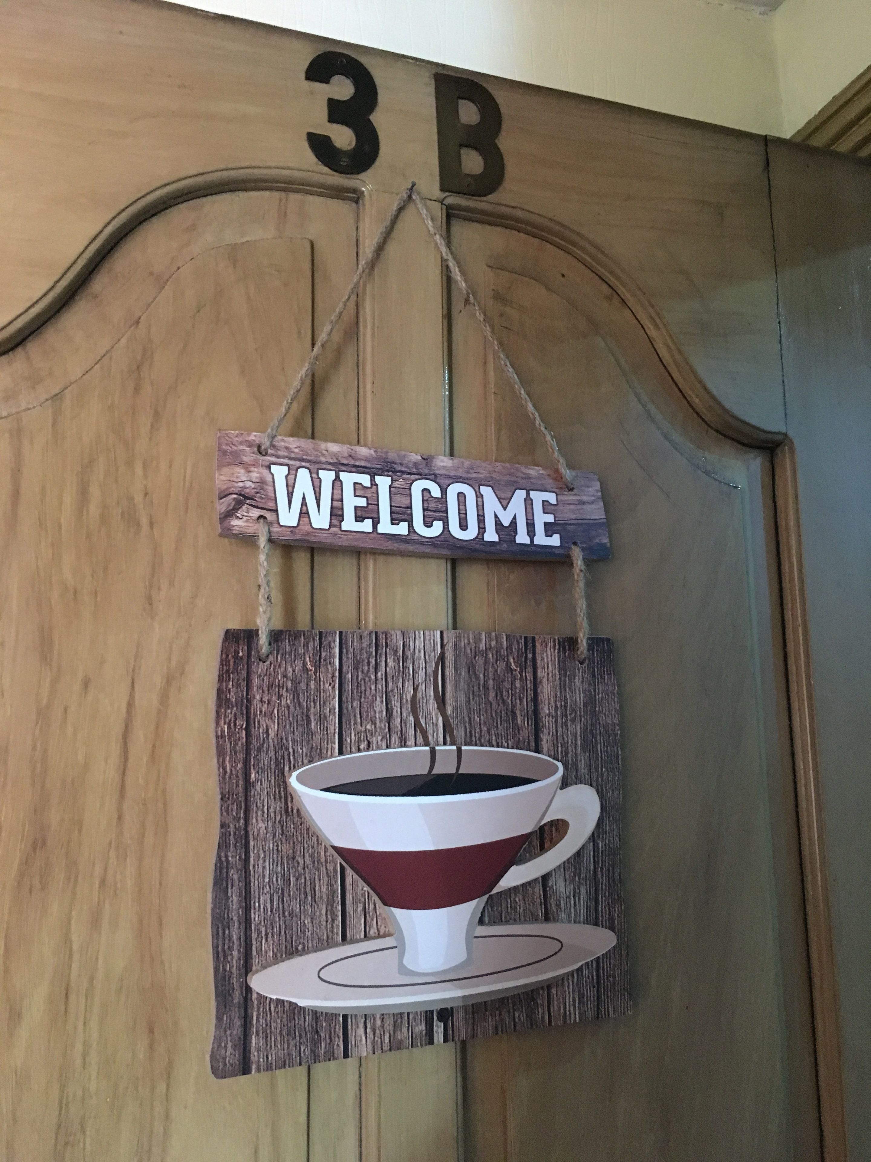 A wooden wall with a 'WELCOME' sign and a coffee cup decoration.