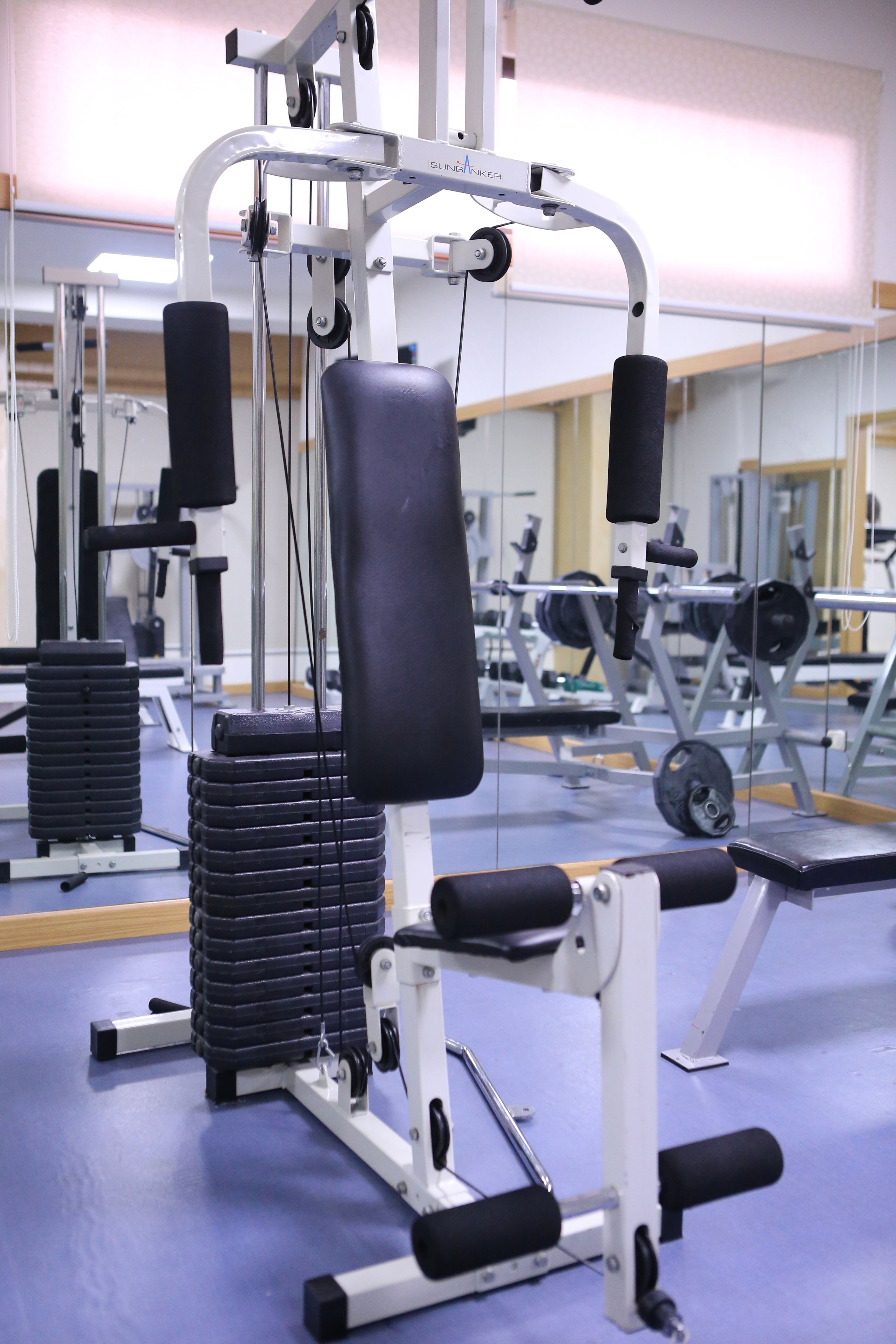 Un gimnasio con diversos equipos de ejercicio, incluyendo pilas de pesas y máquinas.