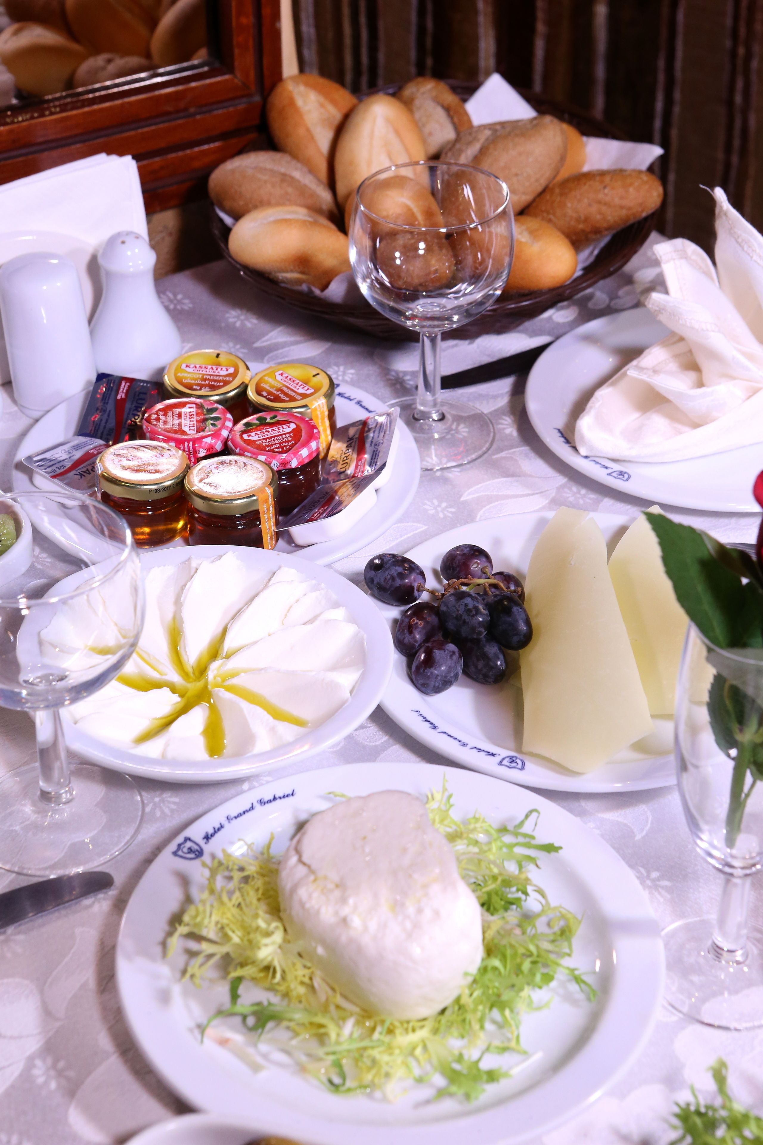 Une table dressée avec divers fromages, des raisins, du pain et des condiments.