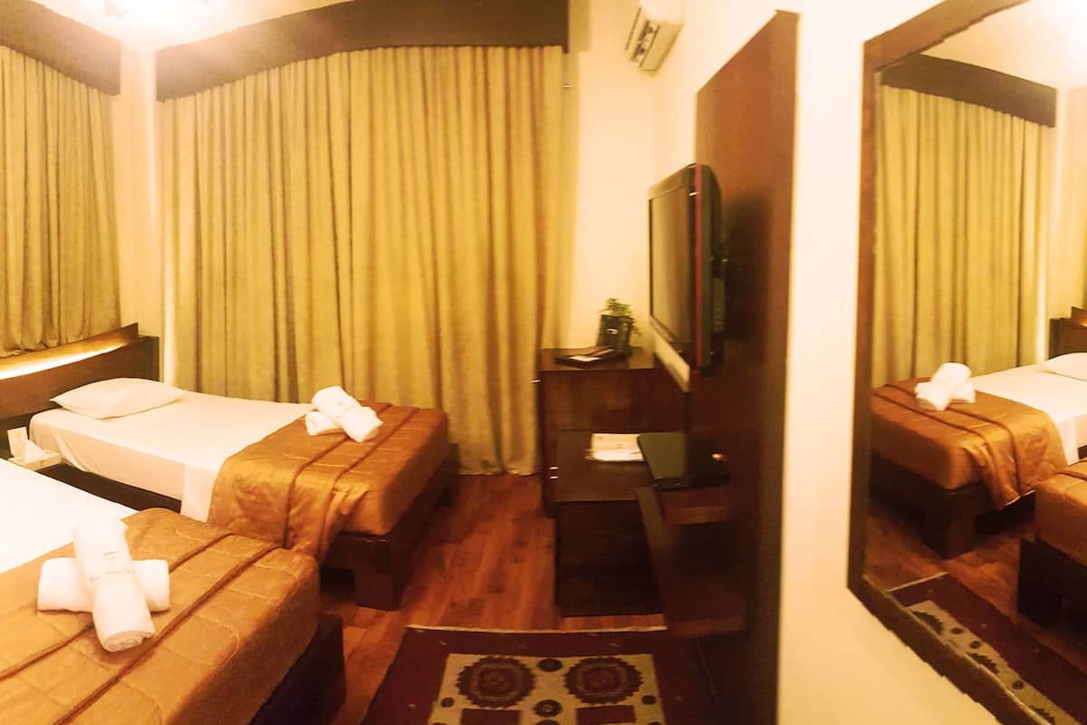 Habitación de hotel con dos camas, televisión, escritorio y espejo.