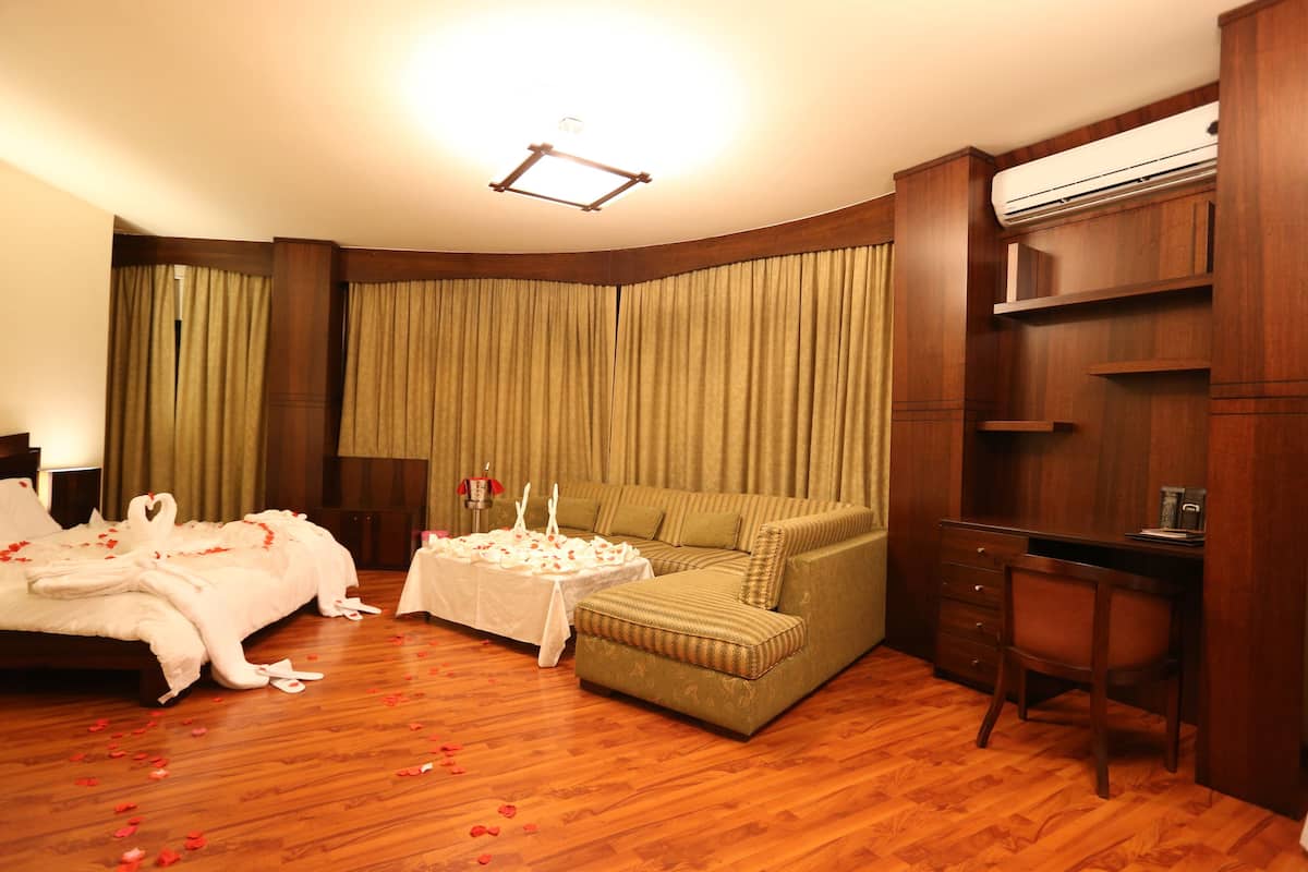 Habitación de hotel con cama, sofá, escritorio y silla.