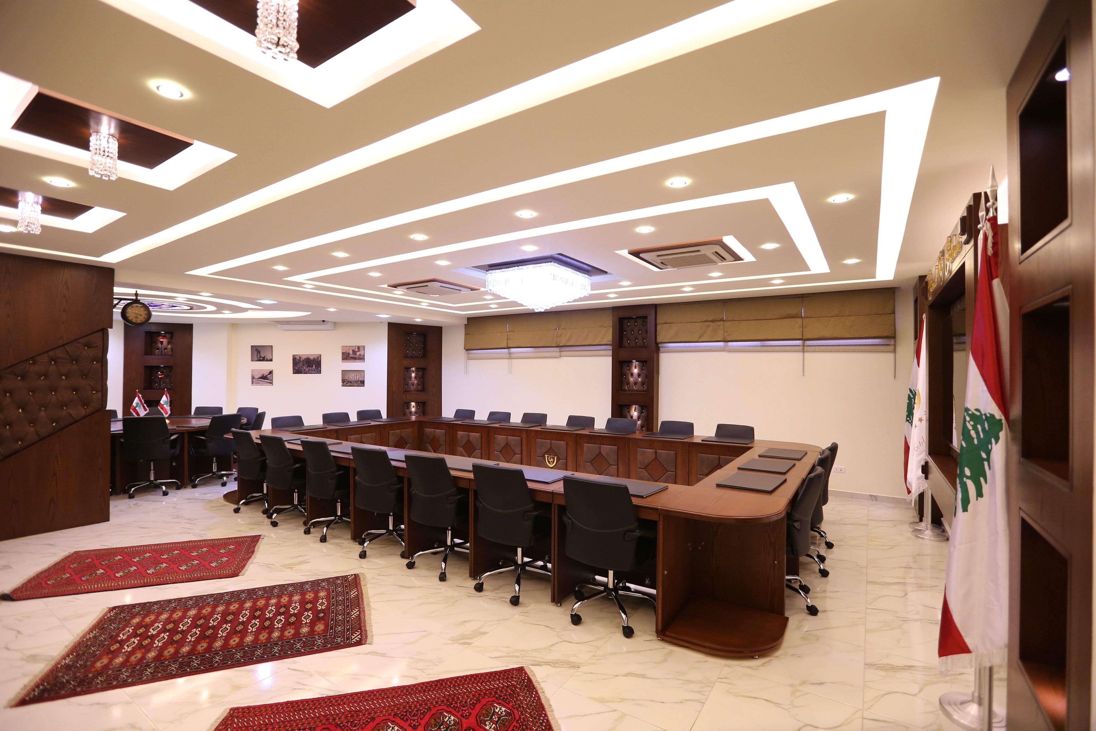 Un salón de conferencias con una larga mesa, sillas y banderas.