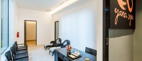 A modern spa room with a reception desk, seating area, and a large mirror.