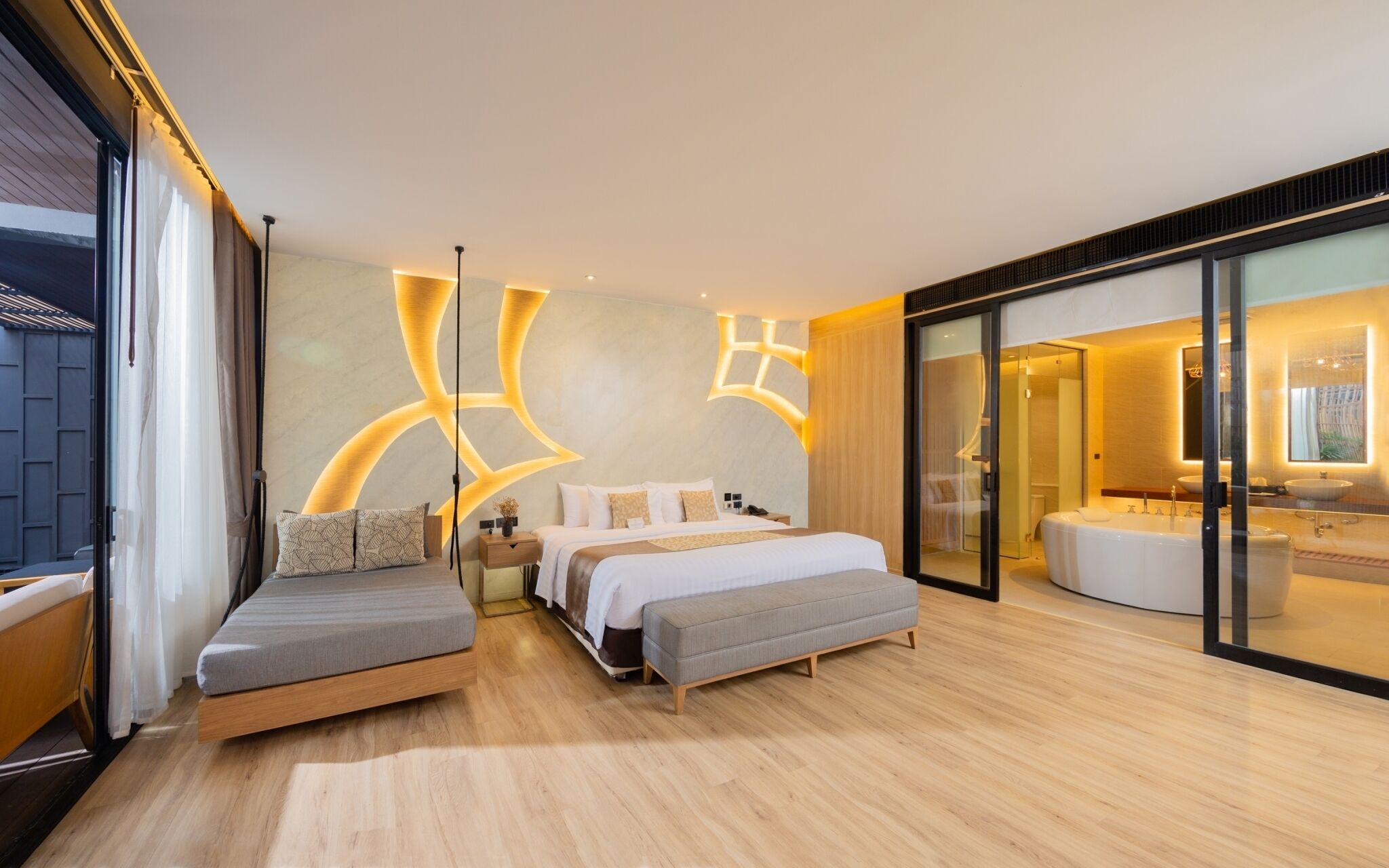 A modern bedroom with a large bed, a sofa, a glass shower area, and a view of the outside.