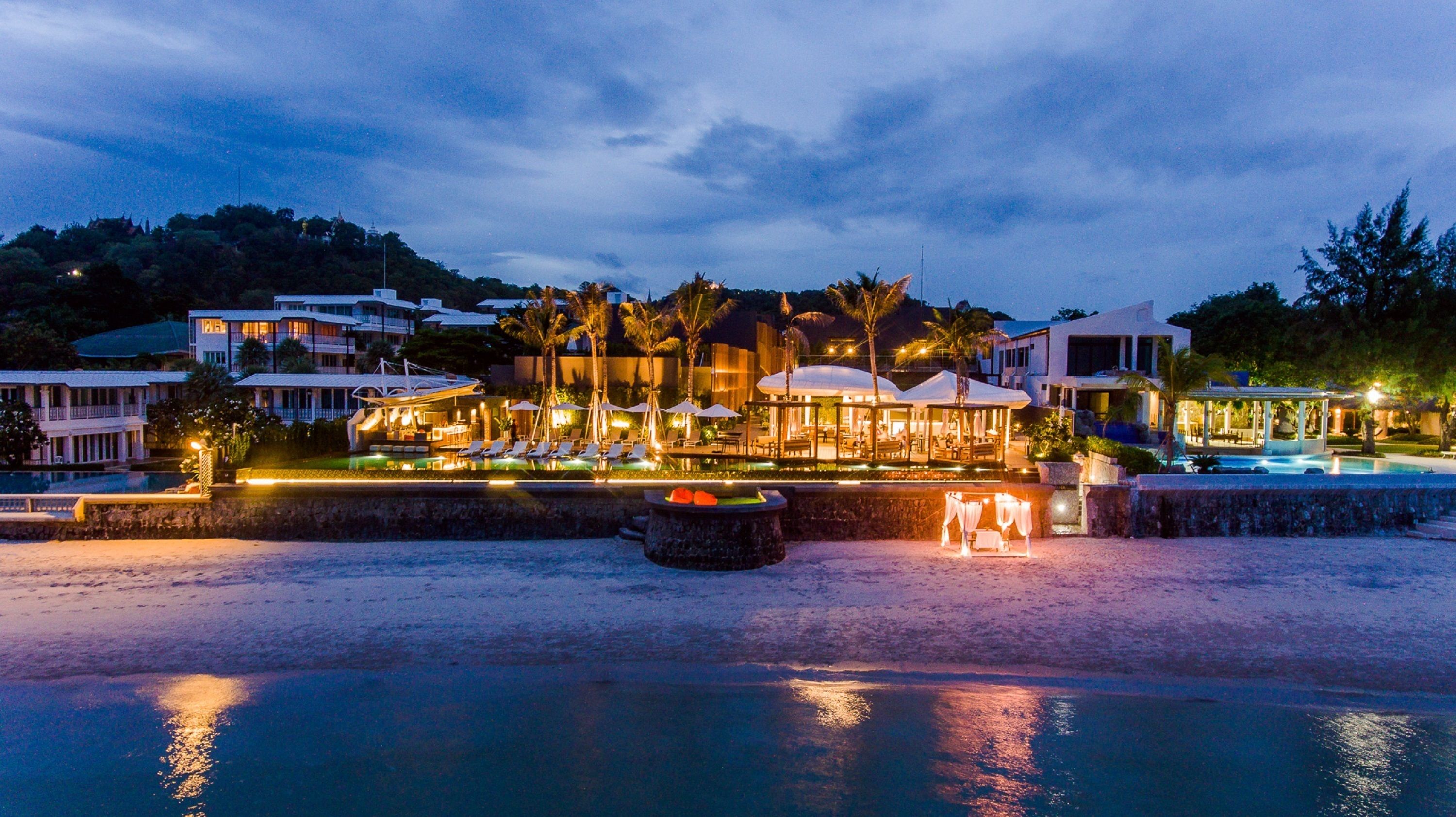A resort with multiple buildings, a swimming pool, and a beachfront area.