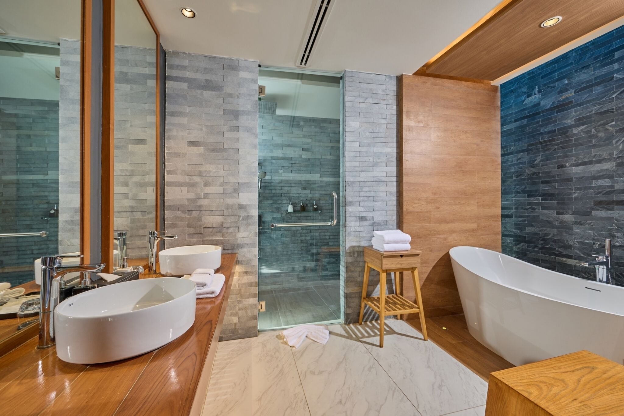 Un baño moderno con una bañera independiente, un espejo grande y una zona de ducha con paredes de vidrio.