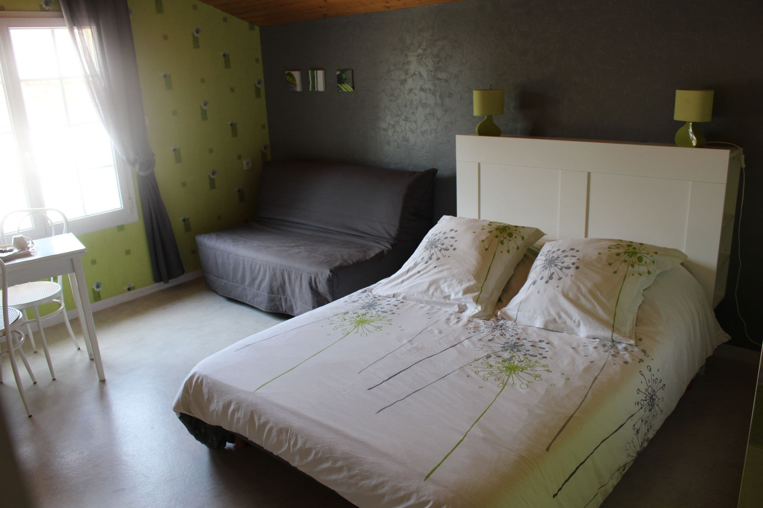 A bedroom with a bed, a chair, a desk, and a lamp.