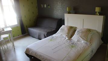 A bedroom with a bed, a chair, a desk, and a lamp.