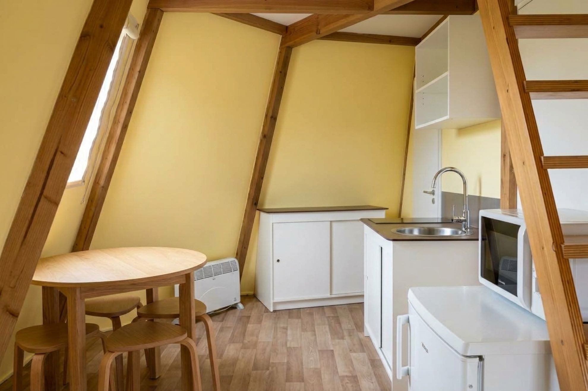A compact kitchen with a dining area, white cabinetry, and a built-in microwave.