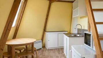 A compact kitchen with a dining area, white cabinetry, and a built-in microwave.
