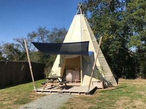 A conical tent with a wooden deck and picnic table in front, surrounded by trees. - La Libaudiere (Pouzauges)