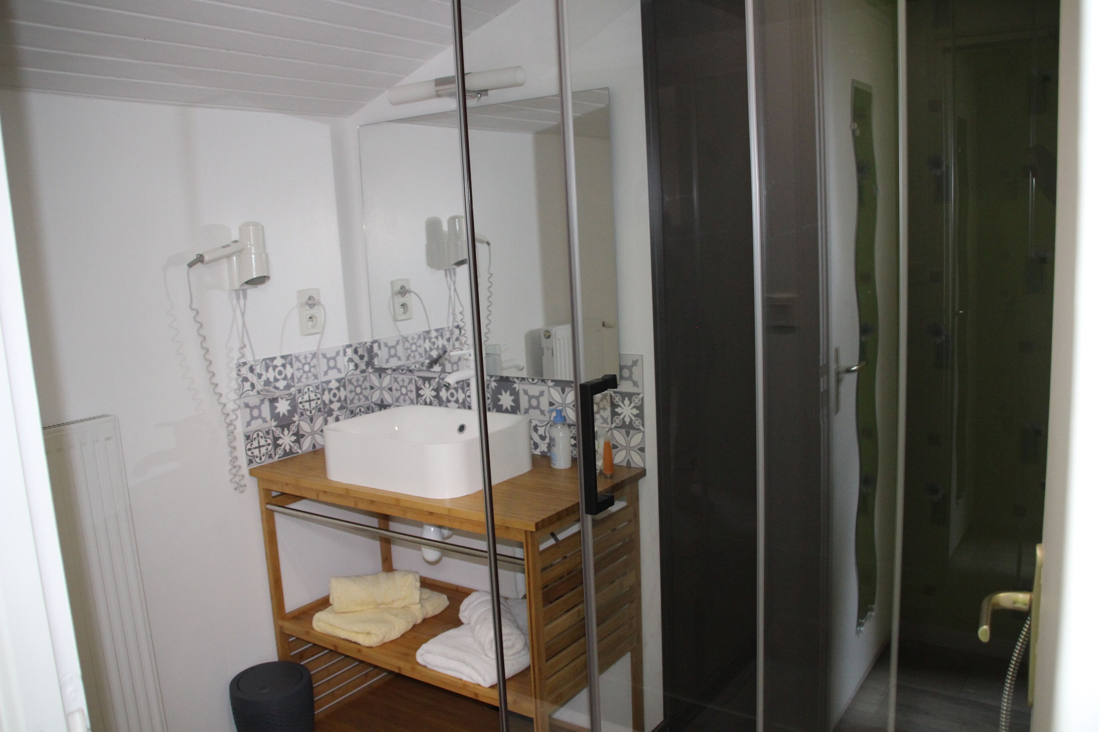 Une salle de bain avec un meuble-lavabo en bois, un lavabo blanc et une cabine de douche en verre.