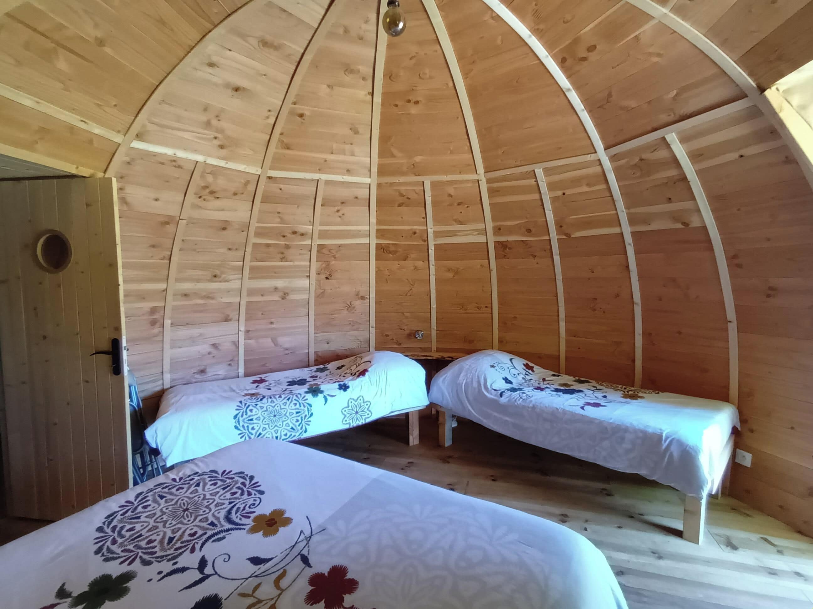 A wooden cabin with two beds, a door, and a circular window.
