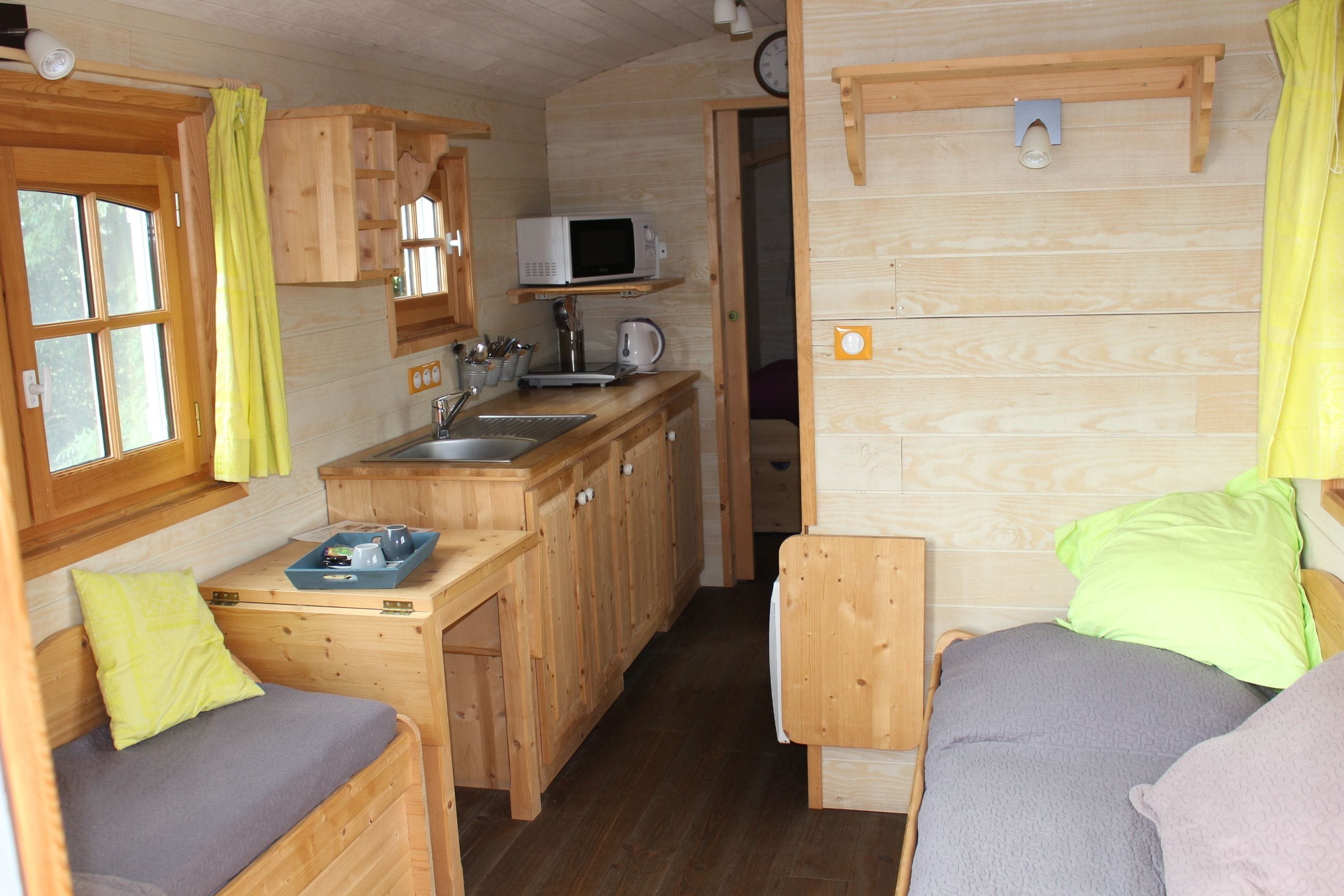 A compact wooden cabin with a kitchenette, a bed, and a small bathroom.