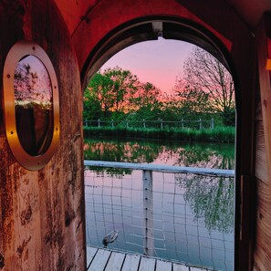 Eine Holzhütte mit einem runden Fenster, das einen Sonnenuntergang widerspiegelt.