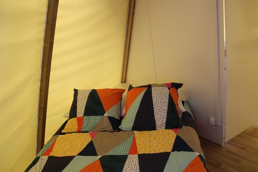 A bed with a colorful quilt and pillows, a wooden floor, and a white door.